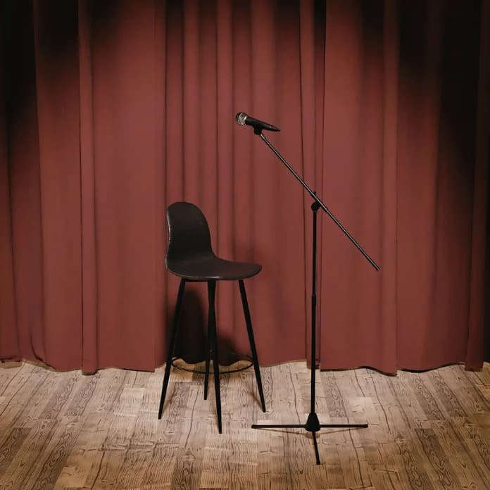 An empty stage with a microphone and a stool